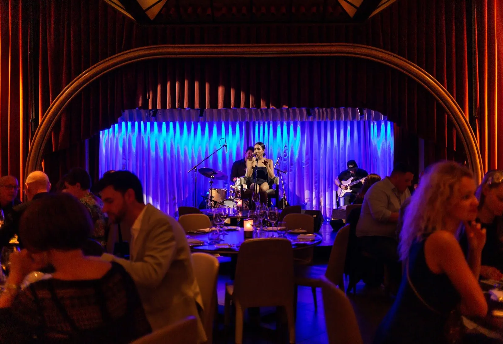 A singer and band perform on the stage at Quaglino's while diners eat at candlelit tables in front