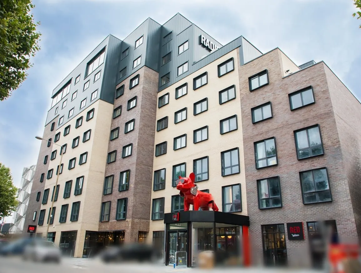 The brick front of Radisson RED London Greenwich The O2, with a red bulldog sculpture above the entrance