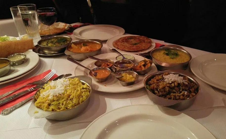 A spread of Keralan dishes at Rasa: lemon rice, dals, a paratha and small steel bowls of curries and pickles across a white tablecloth