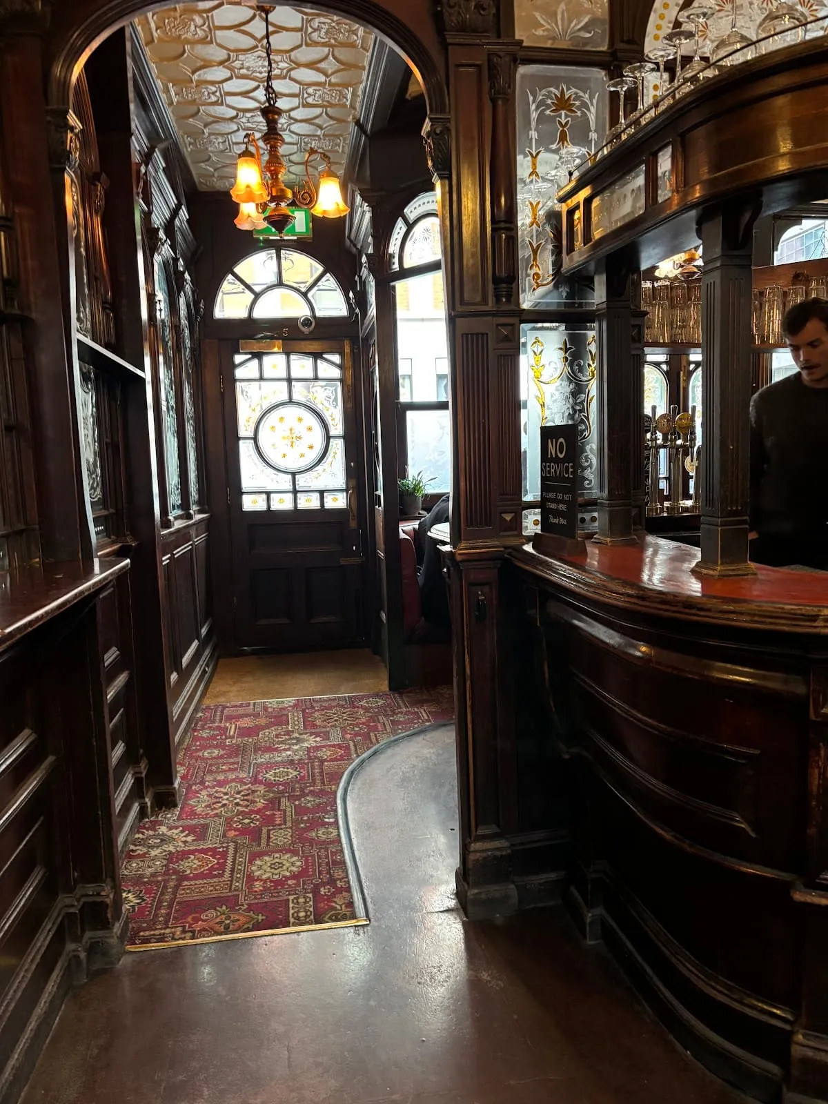 A wood-panelled corridor inside the Red Lion on Duke of York Street, with an etched and stained-glass front door and matching etched mirror panels