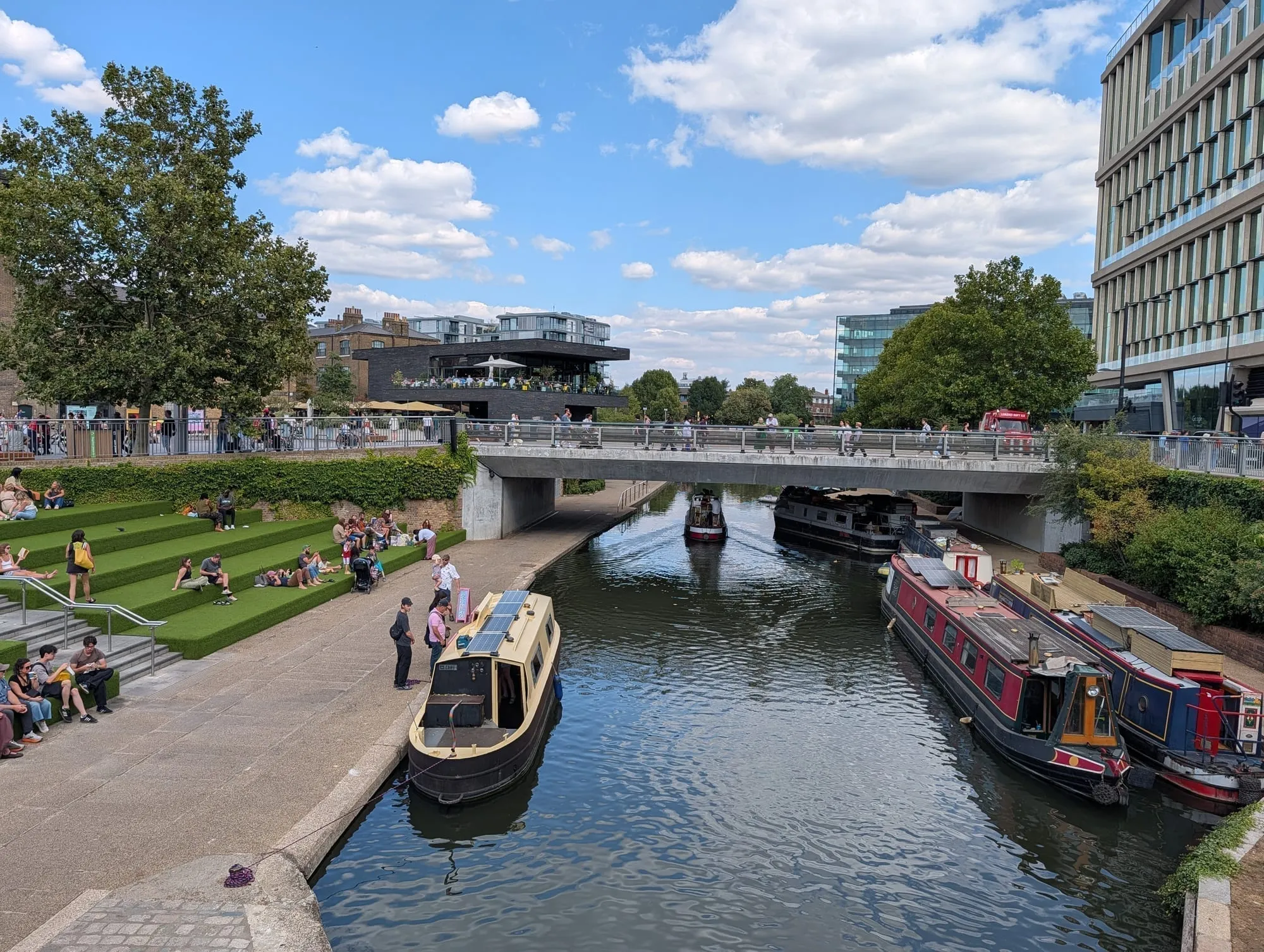 Narrowboats moored on the Regent's Canal beside the grass steps at Granary Square