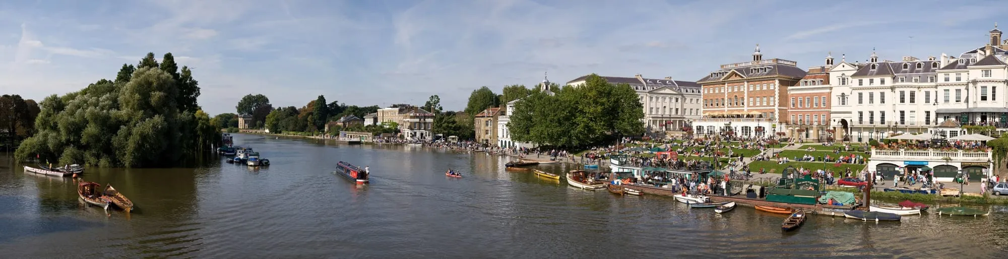 Richmond Riverside on the Thames, with boats moored and people on the grass