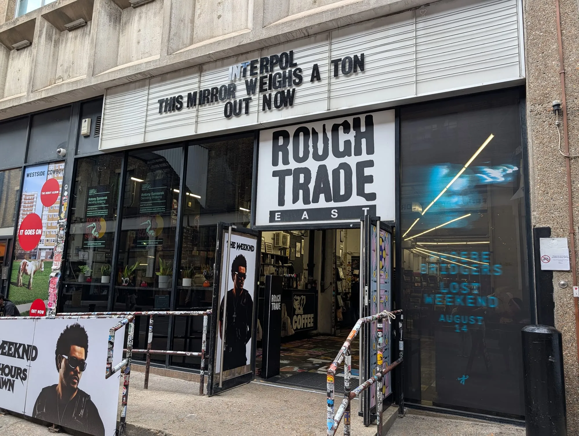 The black frontage of Rough Trade East on Dray Walk, its window display advertising new releases
