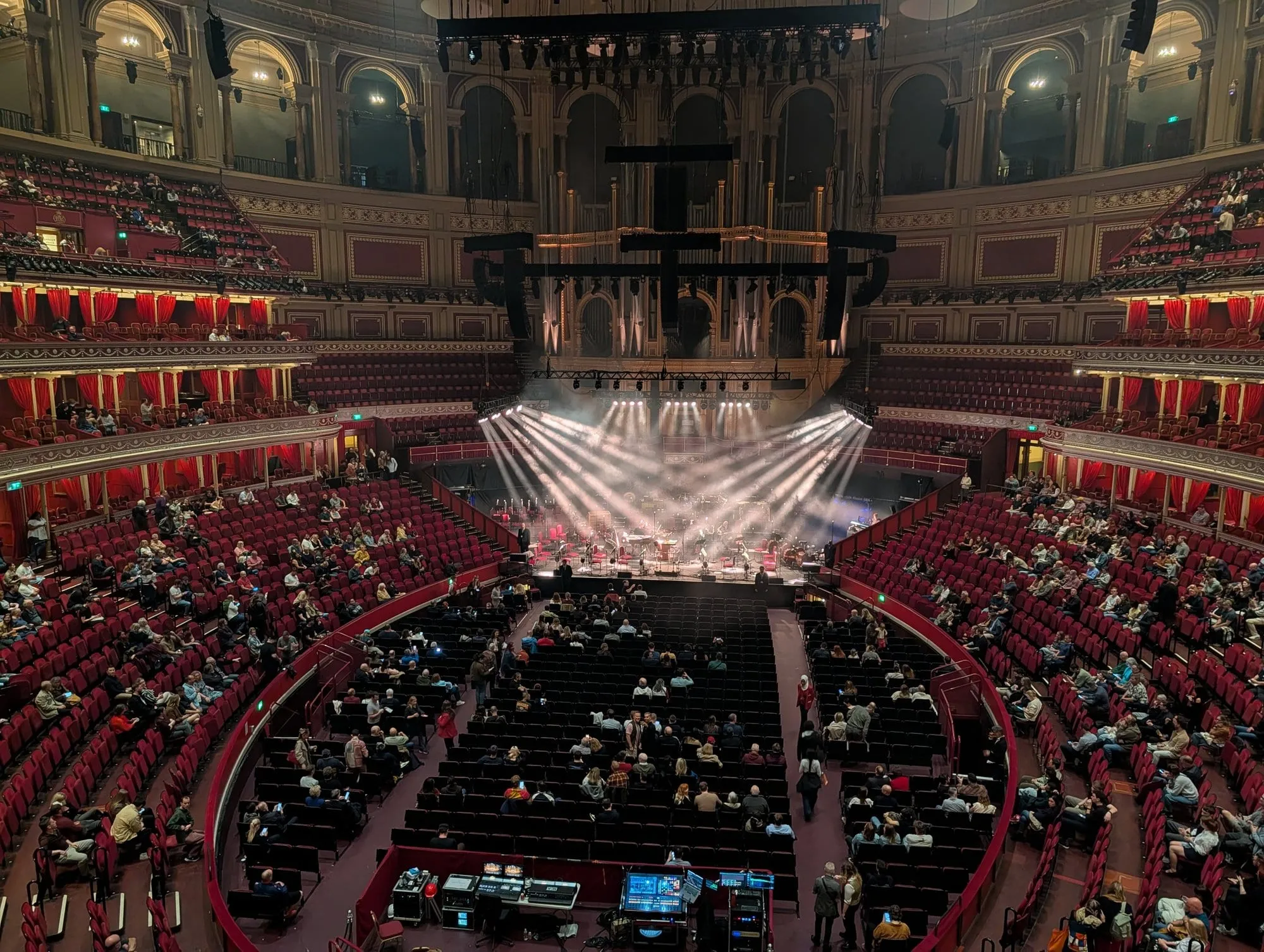 Looking down over the circular auditorium of the Royal Albert Hall mid-concert, with stage lighting and a full audience in the stalls and circle