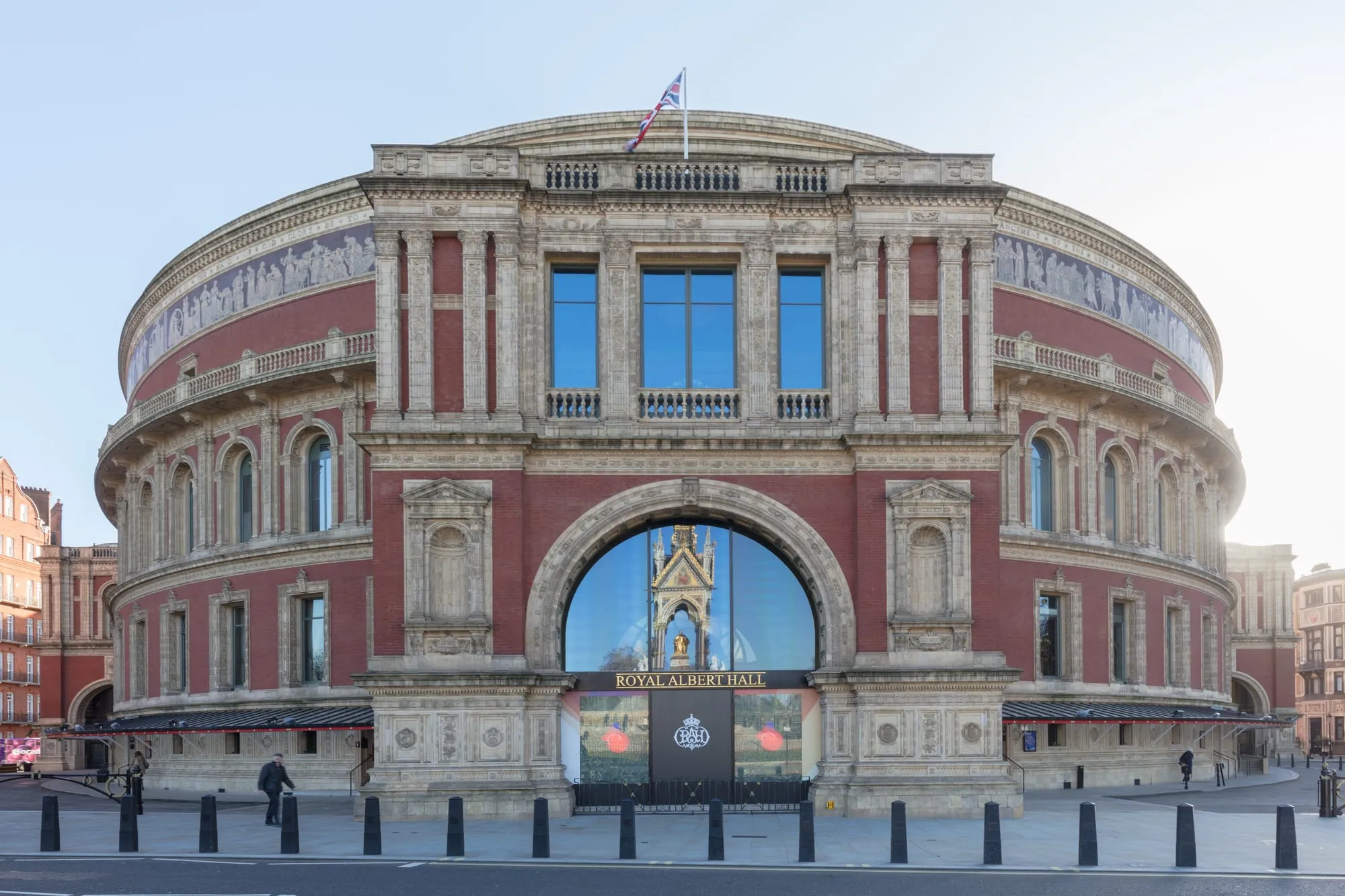 The red-brick Royal Albert Hall with its entrance arch on Kensington Gore, the Albert Memorial reflected in the glass