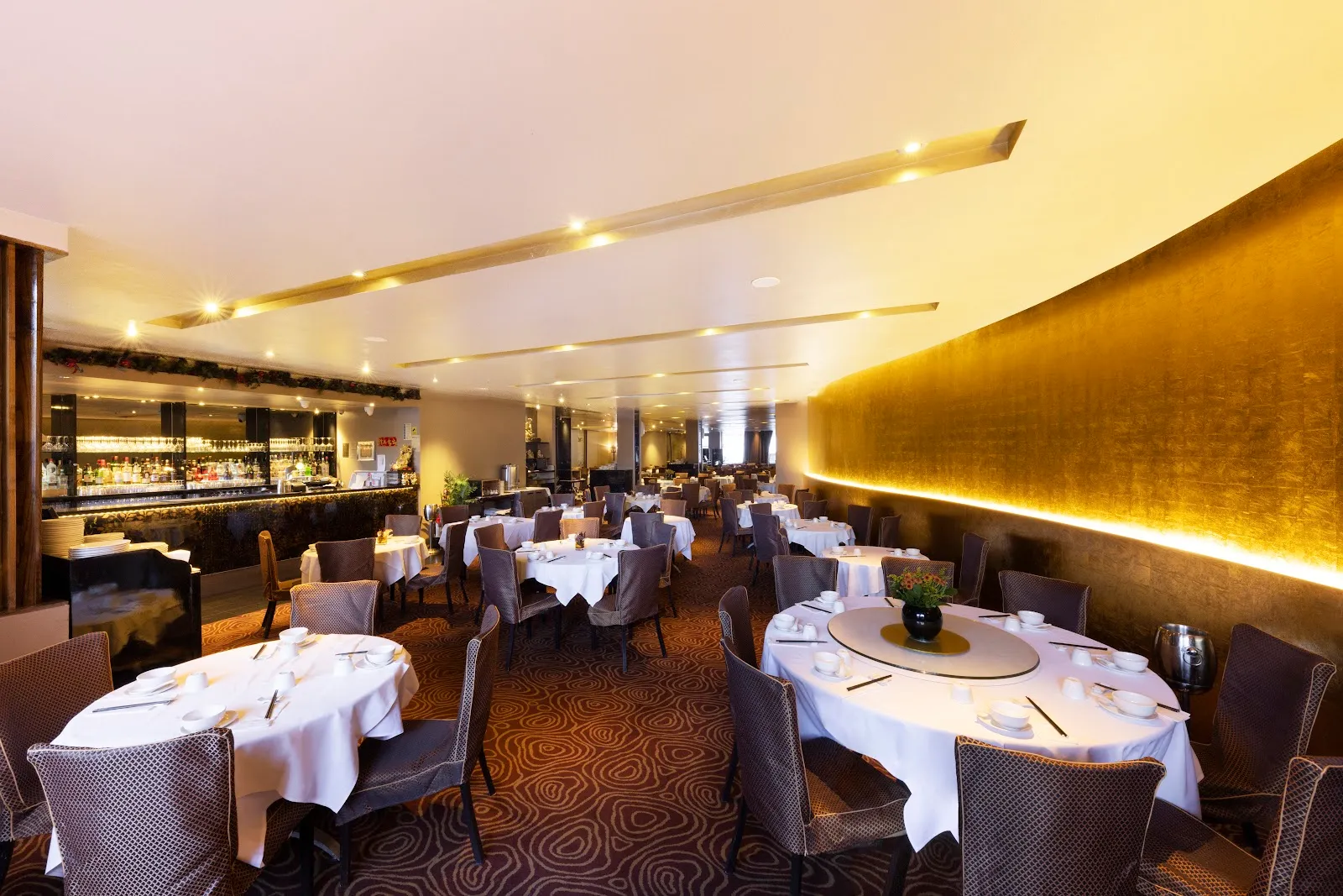 The large, gold-walled dining room at Royal China, set with round tables and lazy susans