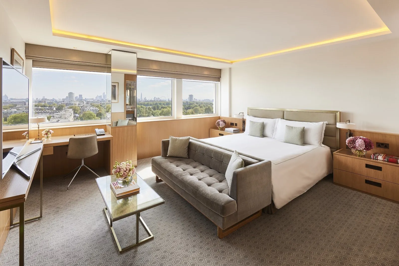 A spacious suite at Royal Lancaster London with a king bed, grey chaise sofa, desk and expansive windows
