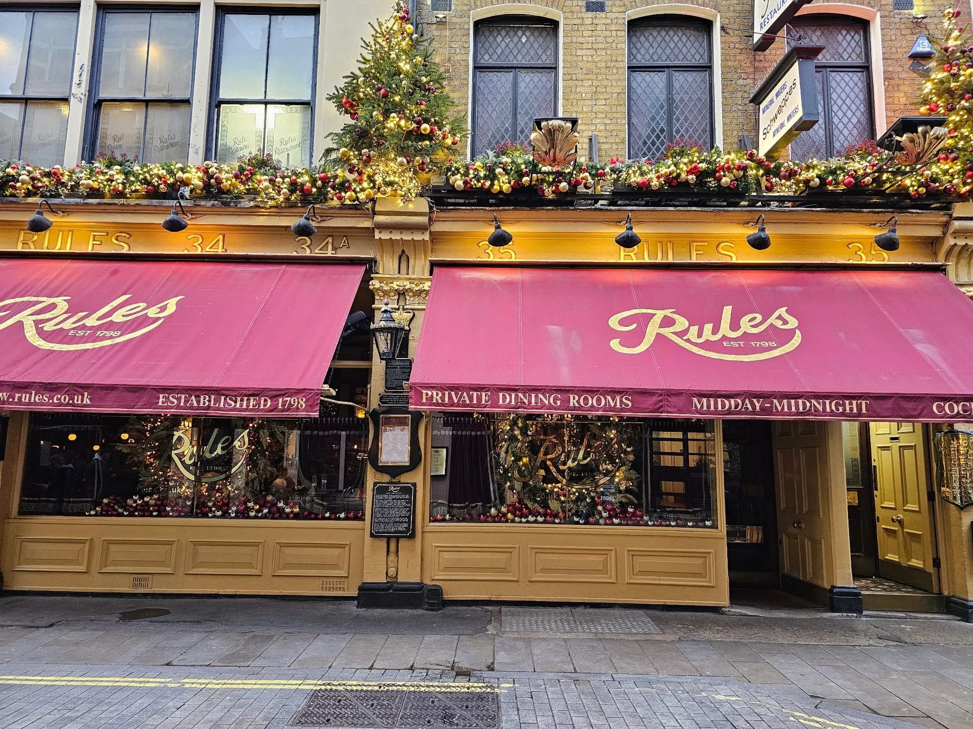 Rules restaurant's maroon awnings and gold lettering on Maiden Lane, reading Rules, Established 1798.