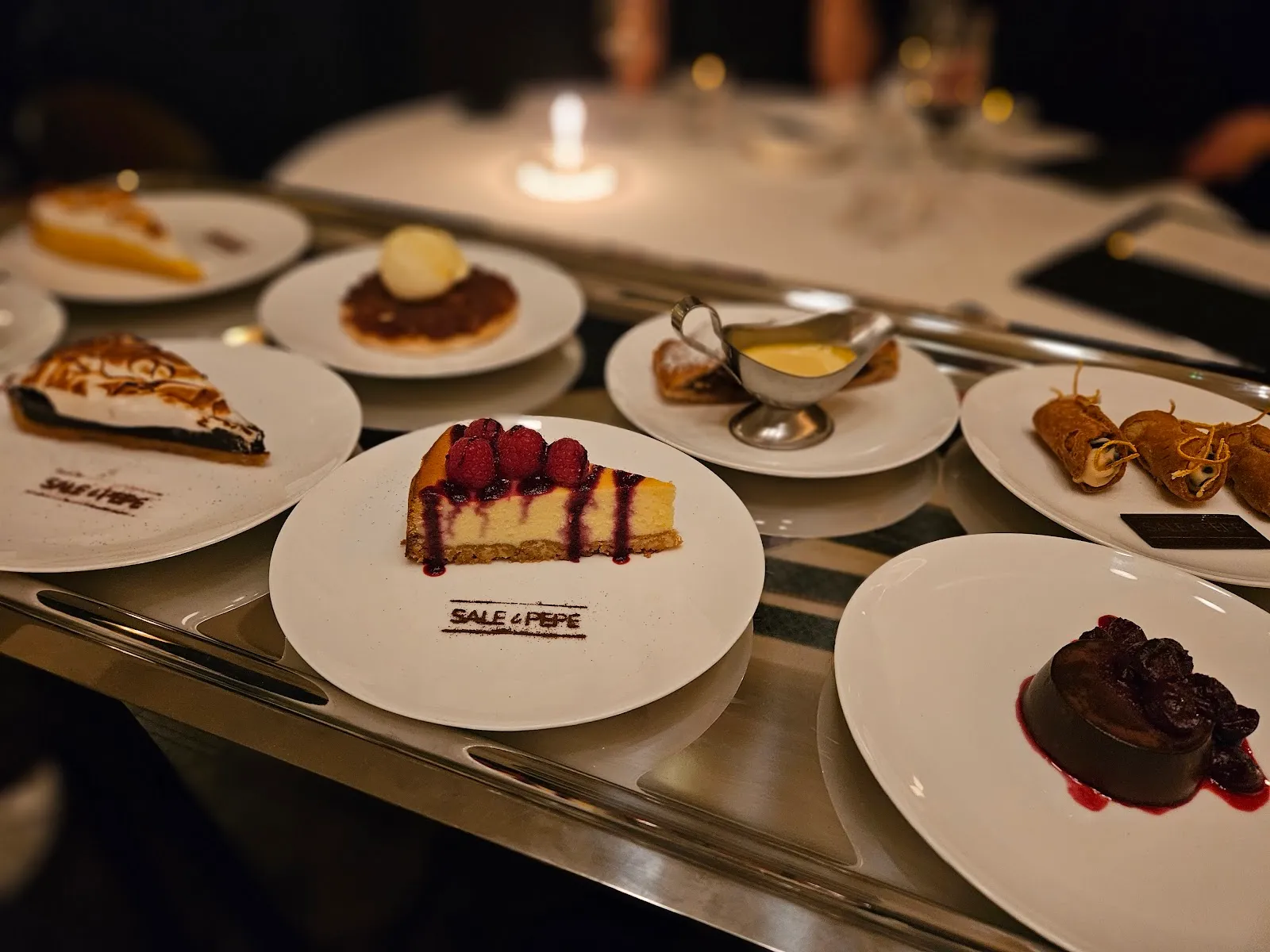 A trolley of desserts including cheesecake, lemon meringue pie and cannoli, plated and ready to serve