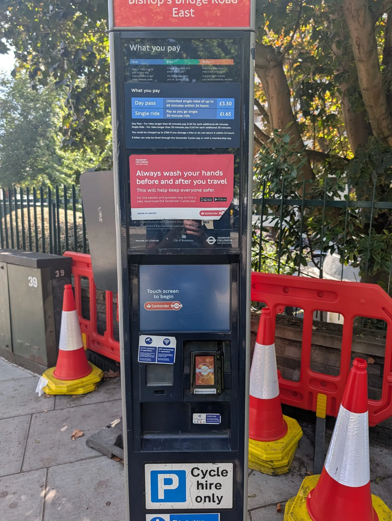 A Santander Cycles docking station terminal, a black screen unit beside red docking points