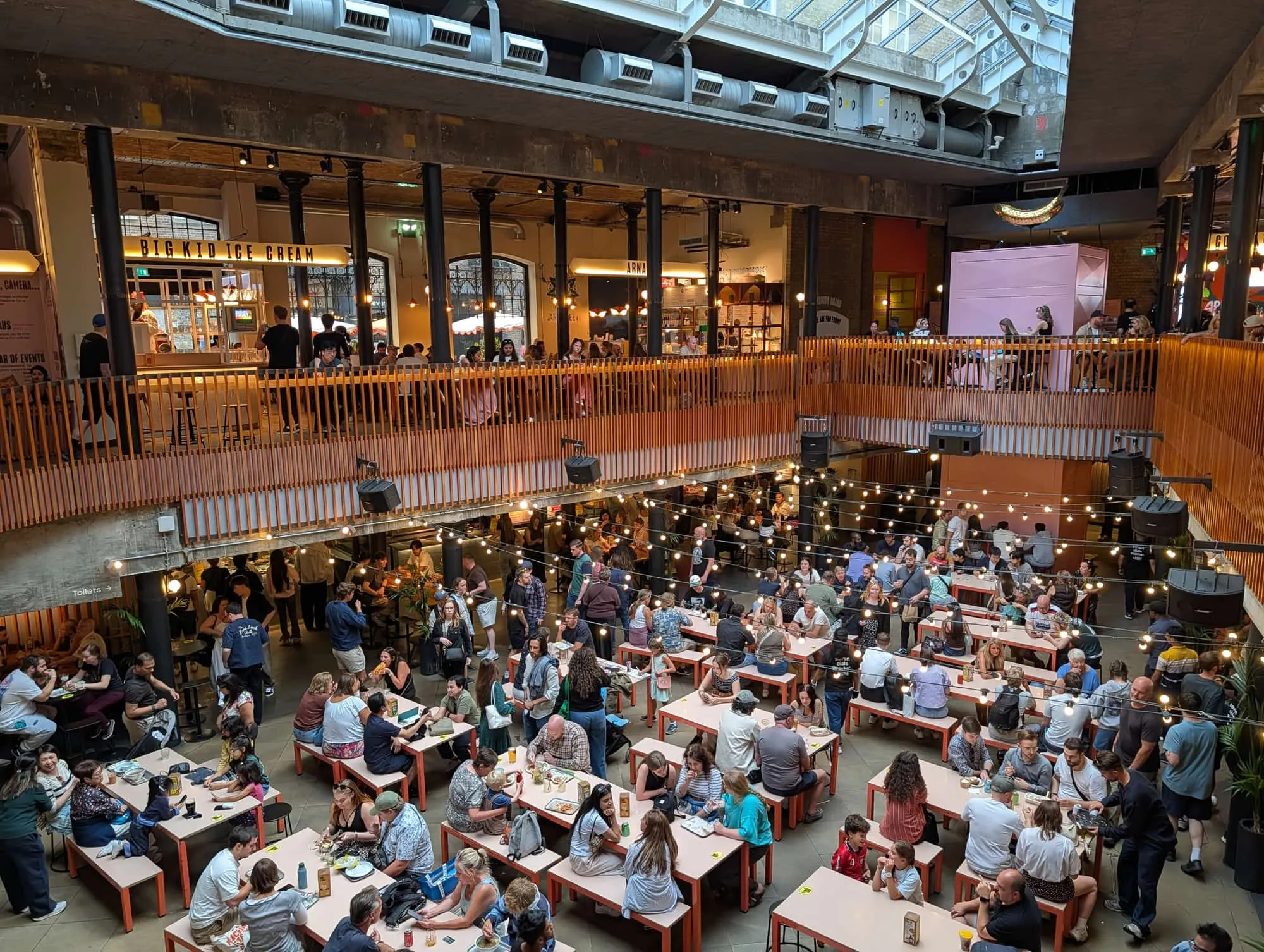 The two-level hall of Seven Dials Market, with communal benches and festoon lighting