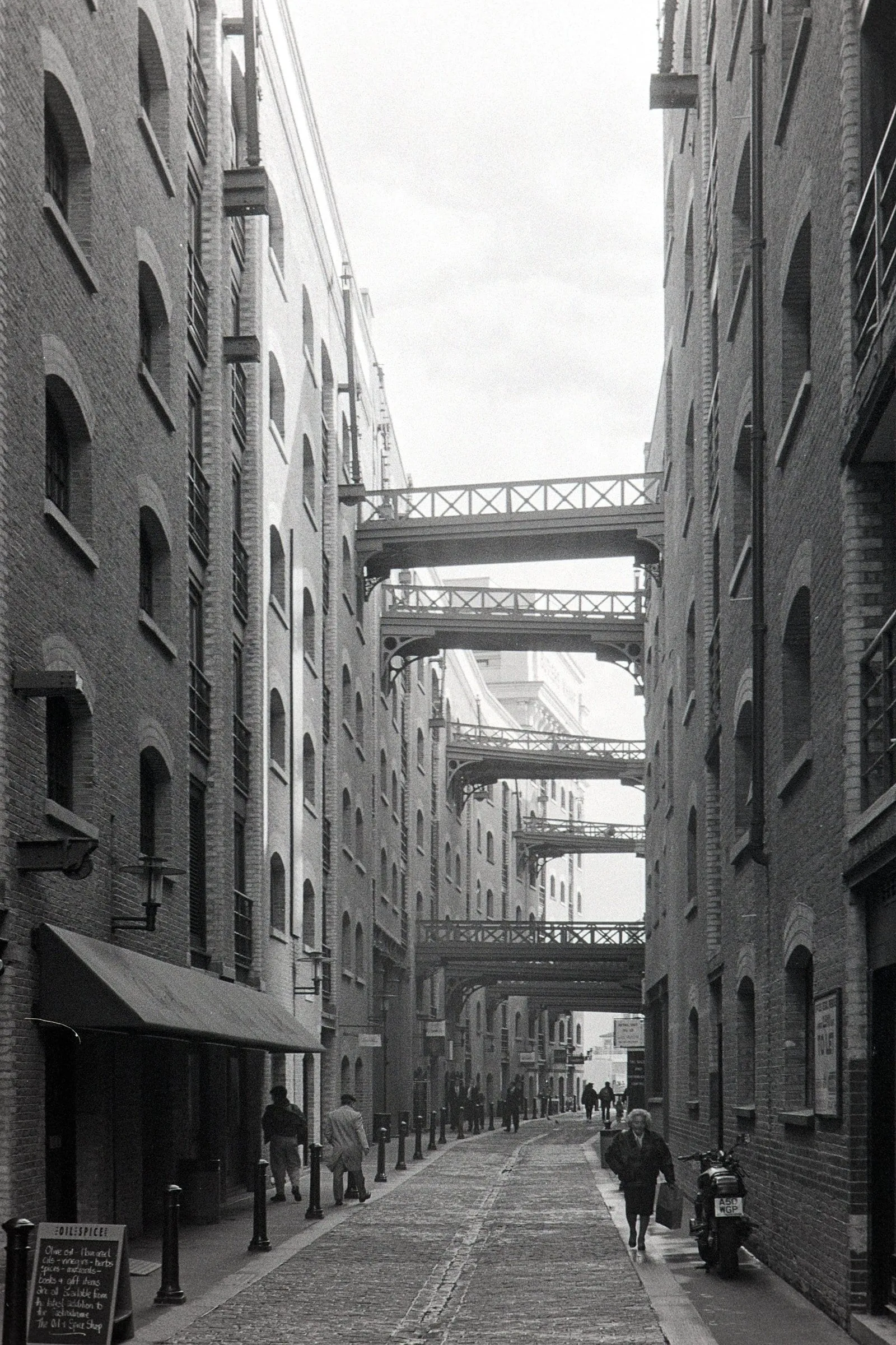 The iron walkways spanning the narrow brick canyon of Shad Thames, in black and white