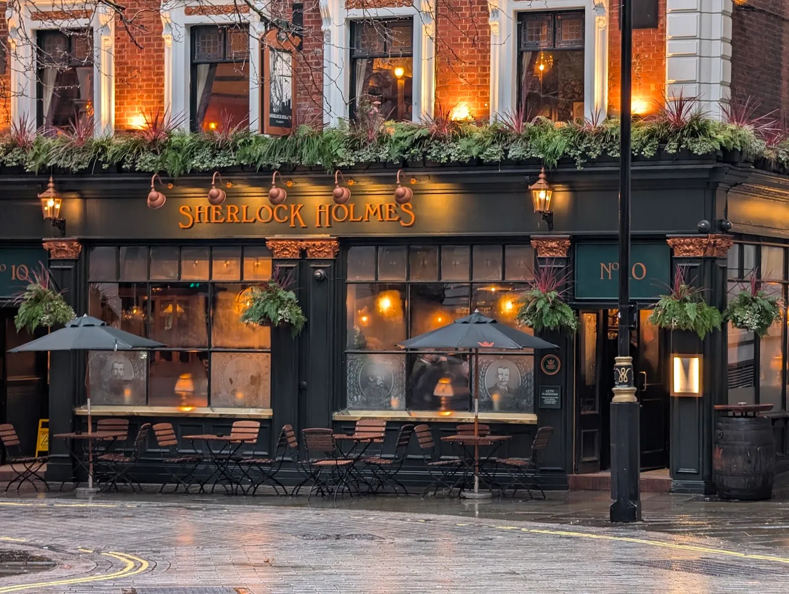 The Sherlock Holmes pub's dark green frontage on Northumberland Street, lit for evening with pavement tables outside