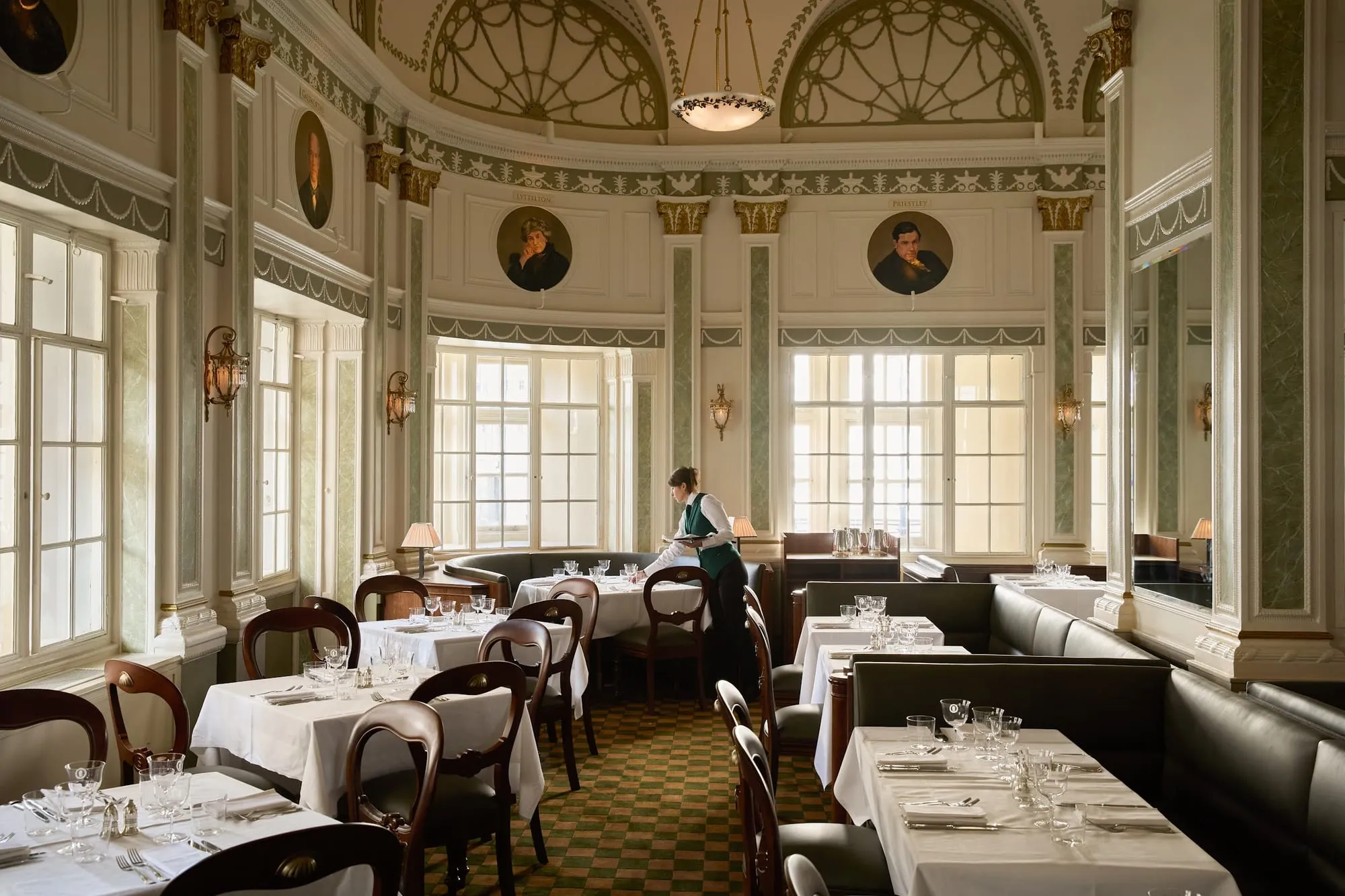 Simpson's-in-the-Strand's domed dining room, with oval portraits mounted below the cornice and white-clothed tables set for service.