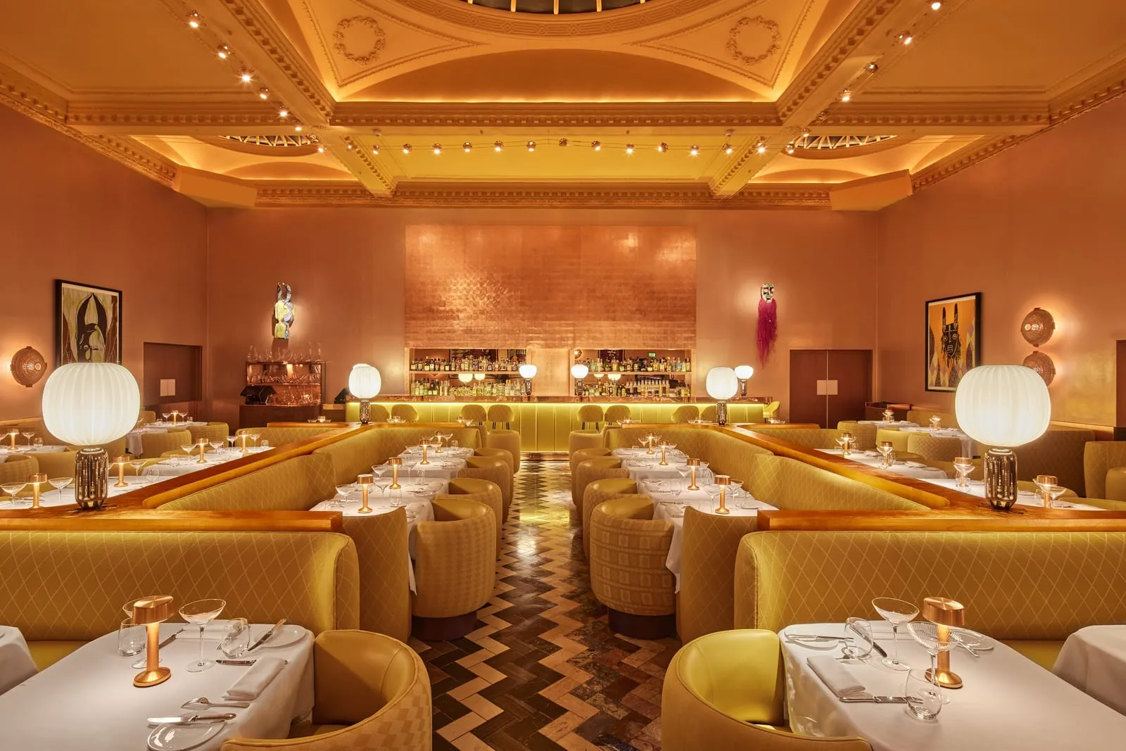 The Gallery at Sketch since its 2022 redesign, long yellow velvet banquettes and white-clothed tables under a gilded ceiling, with artworks on copper-coloured walls