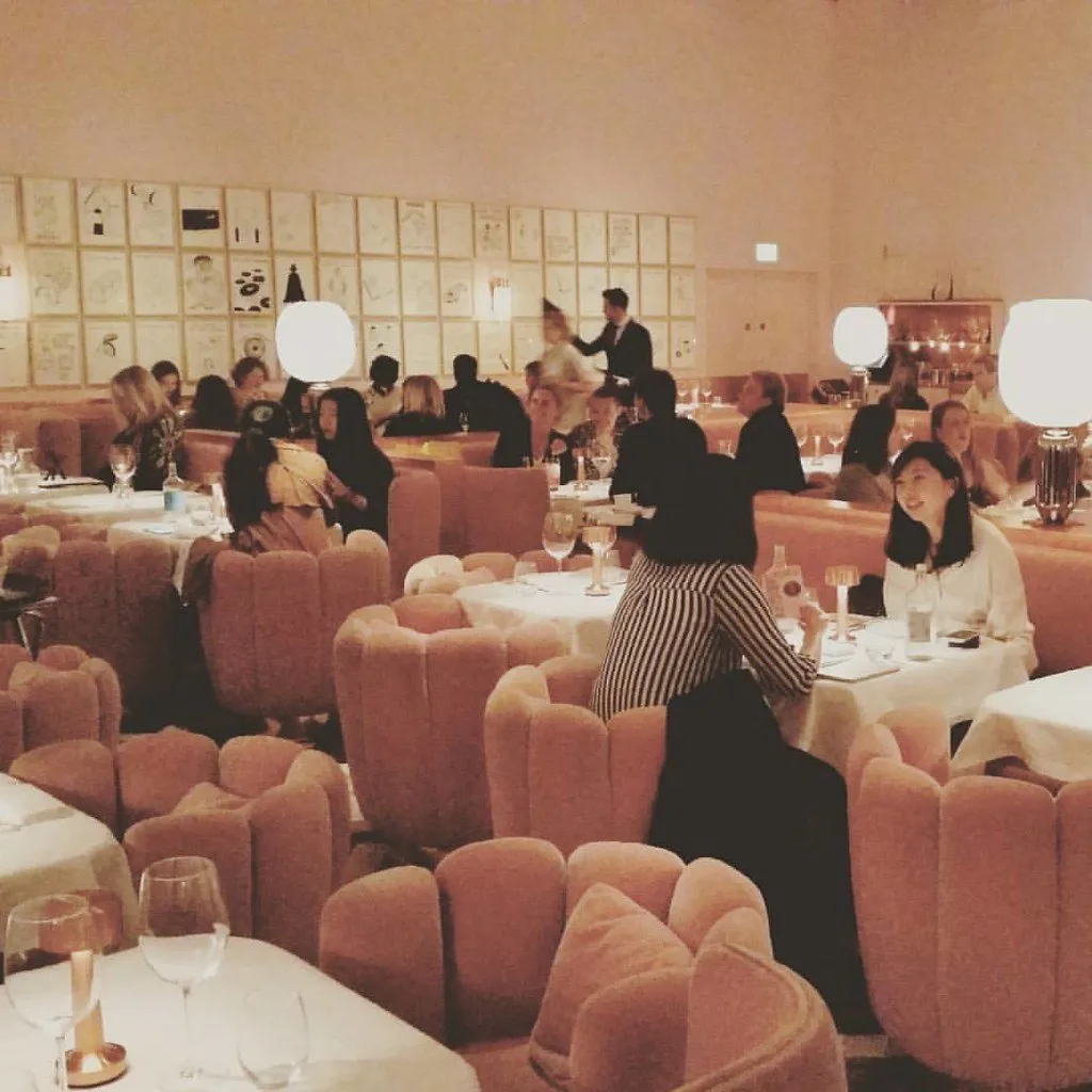The pink upholstered dining room at Sketch, hung with drawings