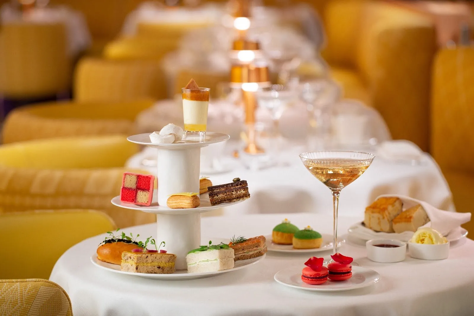A three-tier afternoon tea stand on a table in a yellow dining room