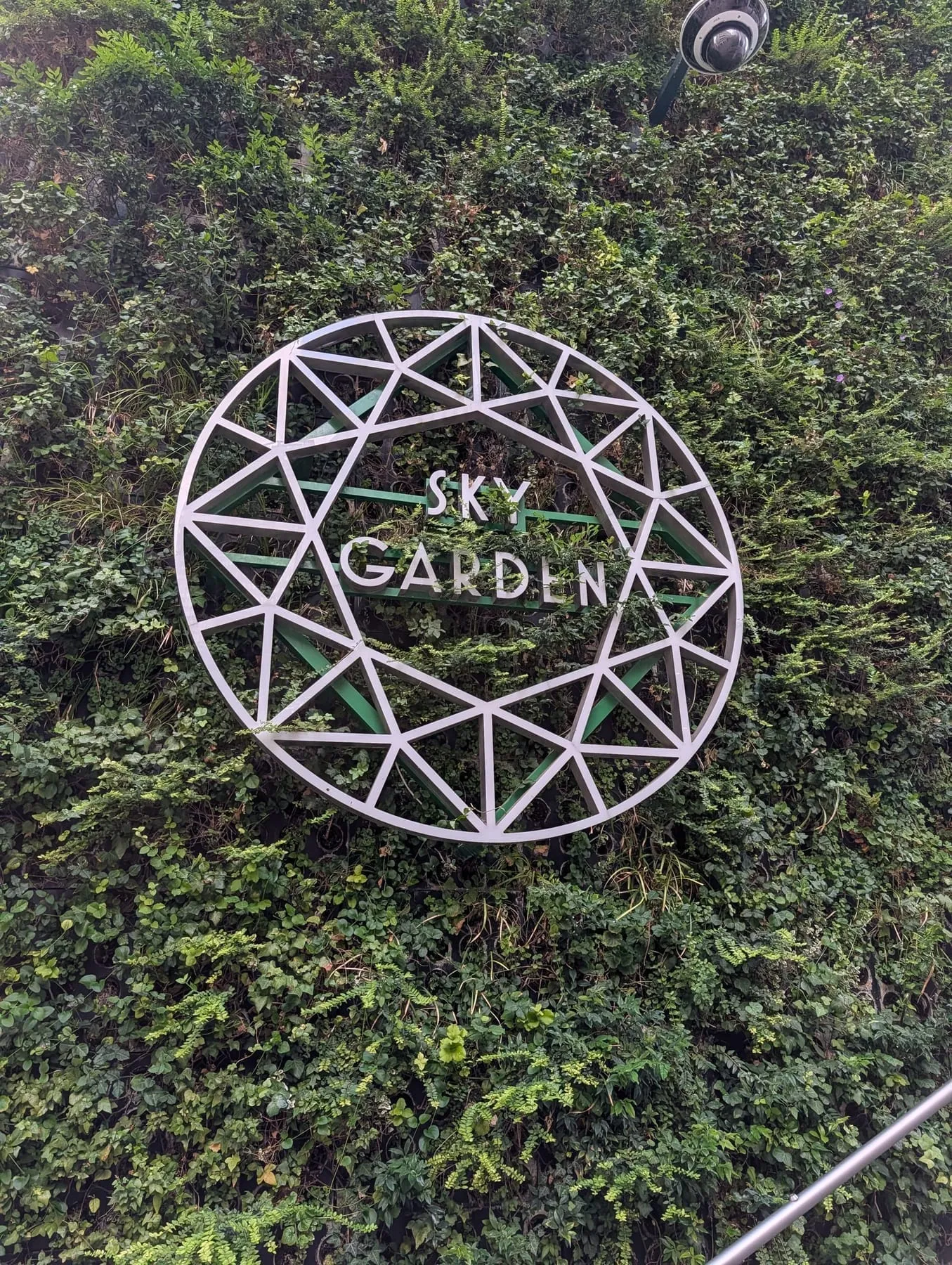 A Sky Garden sign among dense planting inside the glass shell on top of the Walkie-Talkie
