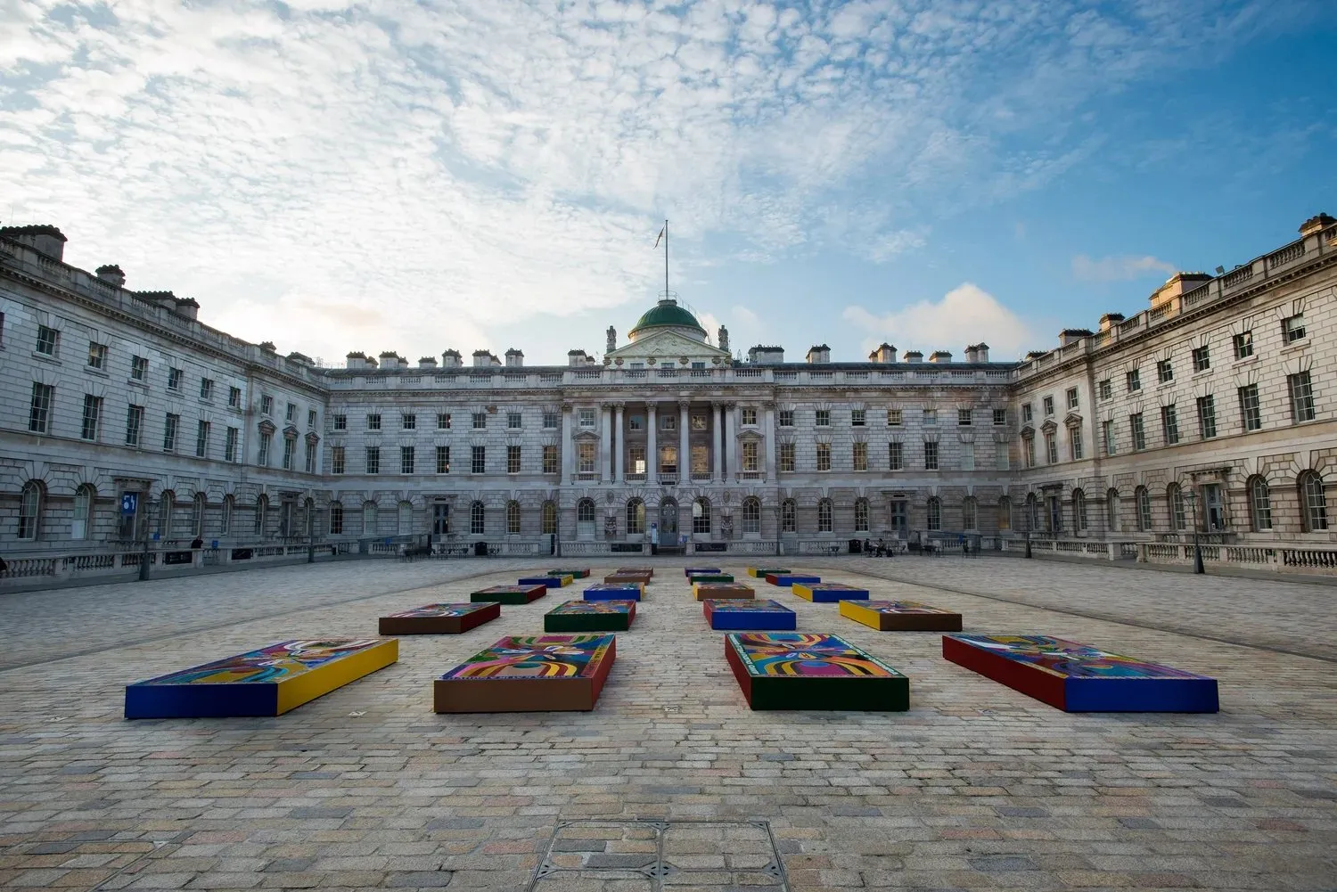 Somerset House's courtyard, with the neoclassical building and its central dome behind a row of colourful sculpture plinths