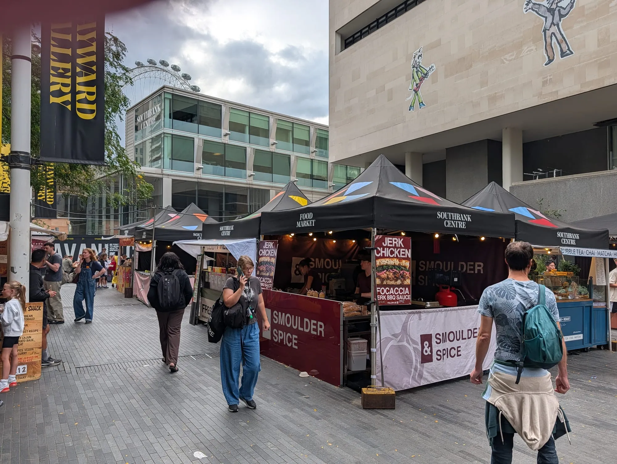 Black gazebos of the Southbank Centre Food Market with a jerk chicken stall in front
