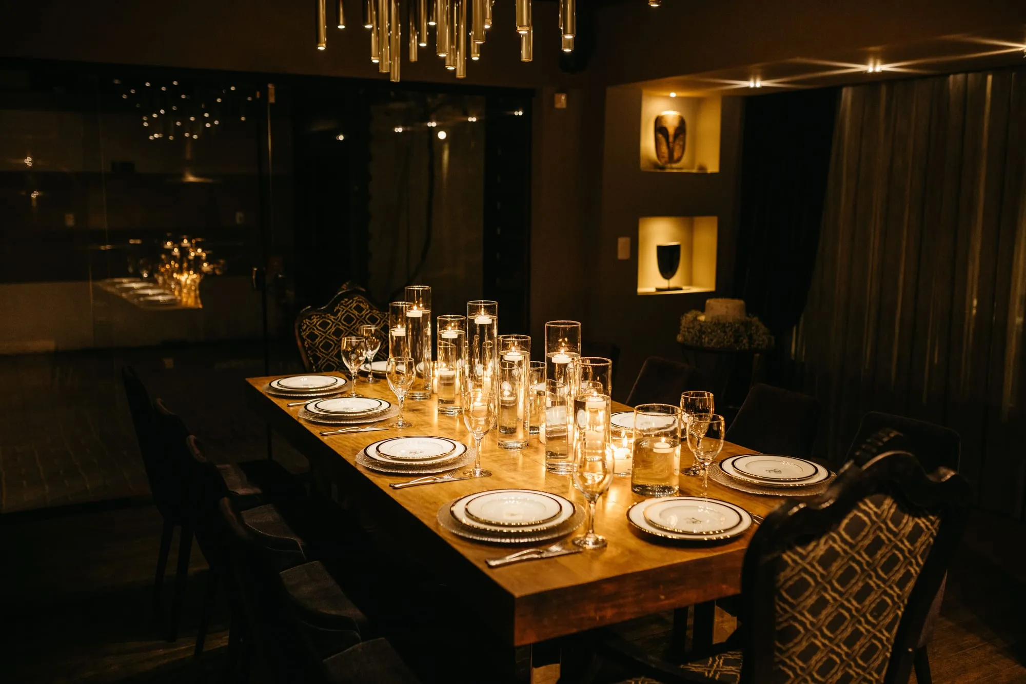 A long table set with candles and glassware in a darkened private dining room