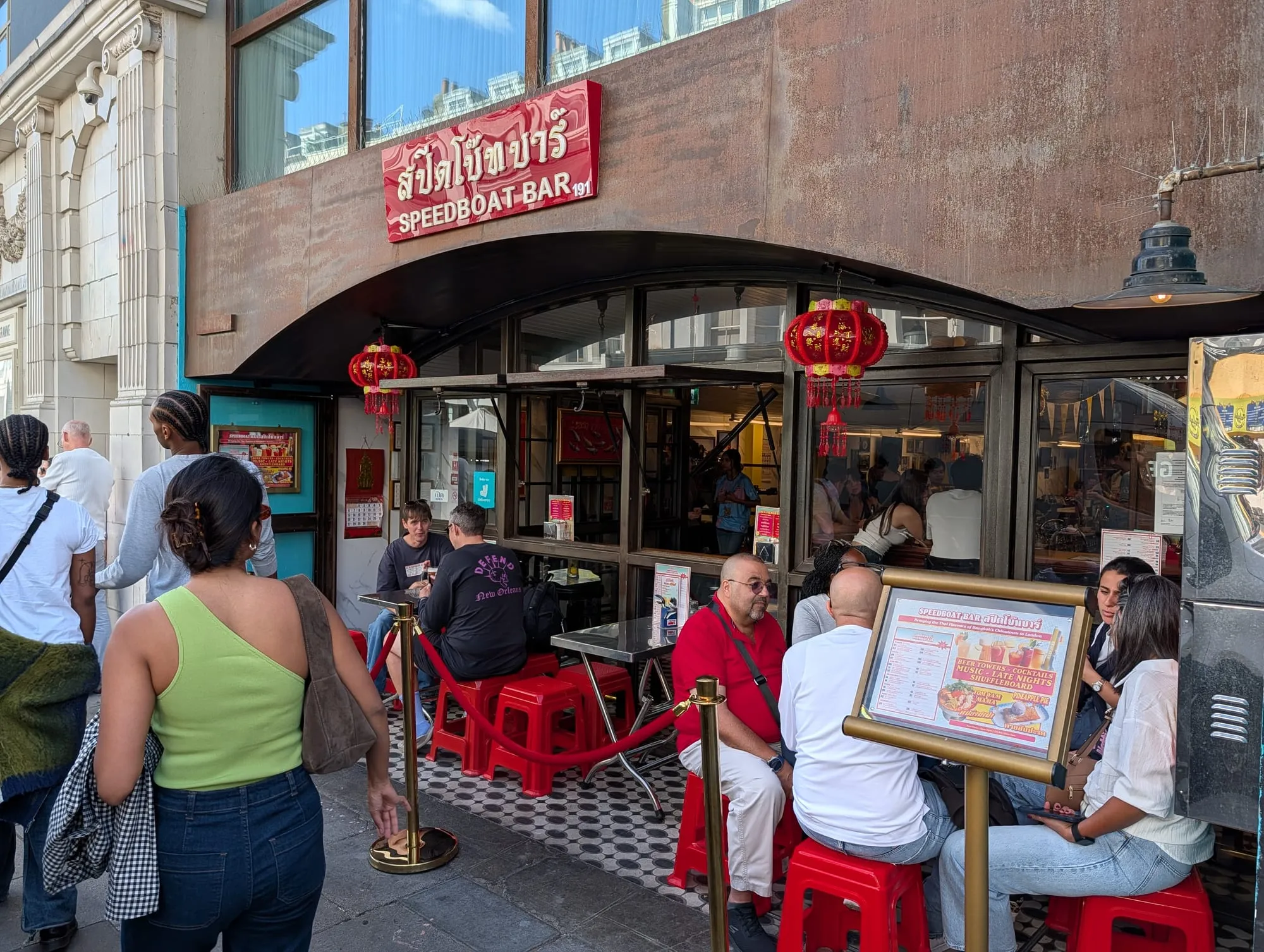 The Speedboat Bar frontage at Electric House on Portobello Road, Thai signage and red paper lanterns over pavement tables with red stools