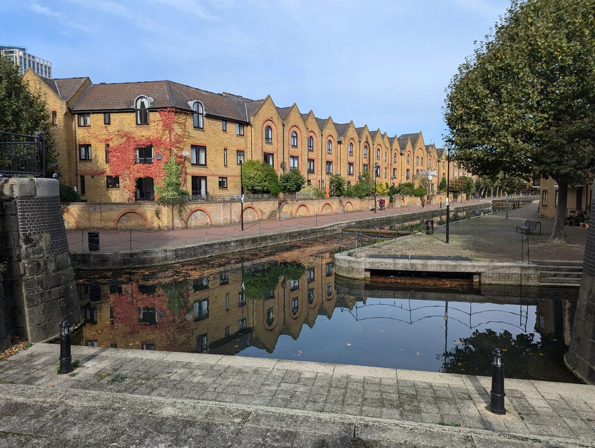 A terrace of gabled brick townhouses at Spirit Quay reflected in the still water of a dock basin