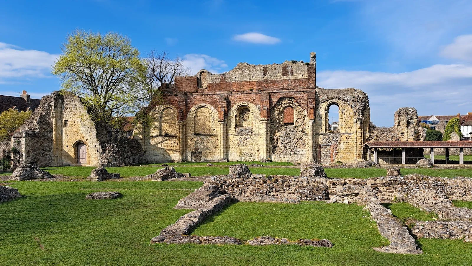 The ruins of St Augustine's Abbey in Canterbury, stone and brick arches standing above a lawn and low foundation walls
