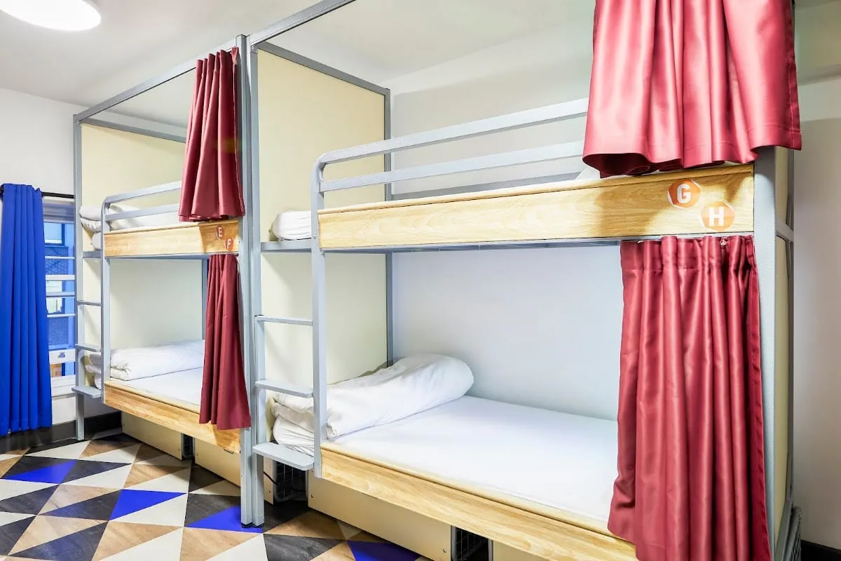 A dorm room at St Christopher's Village, with steel bunk beds and privacy curtains that close off each bed