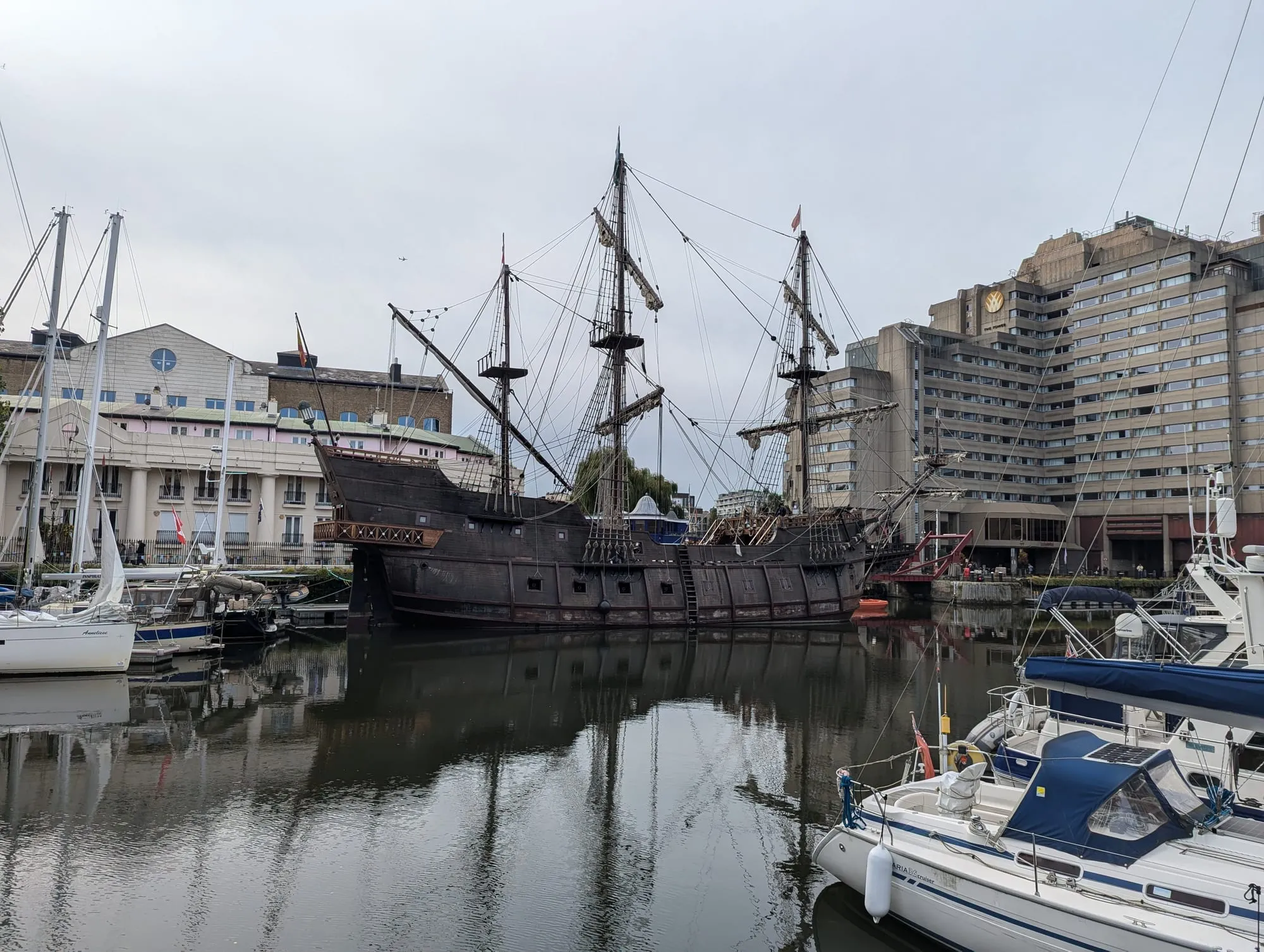 A replica tall ship moored among yachts in St Katharine Docks marina