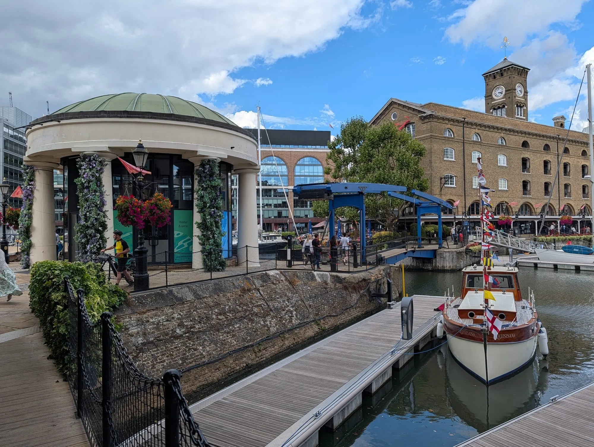 Yachts moored in St Katharine Docks beside a domed bandstand and the old warehouse buildings