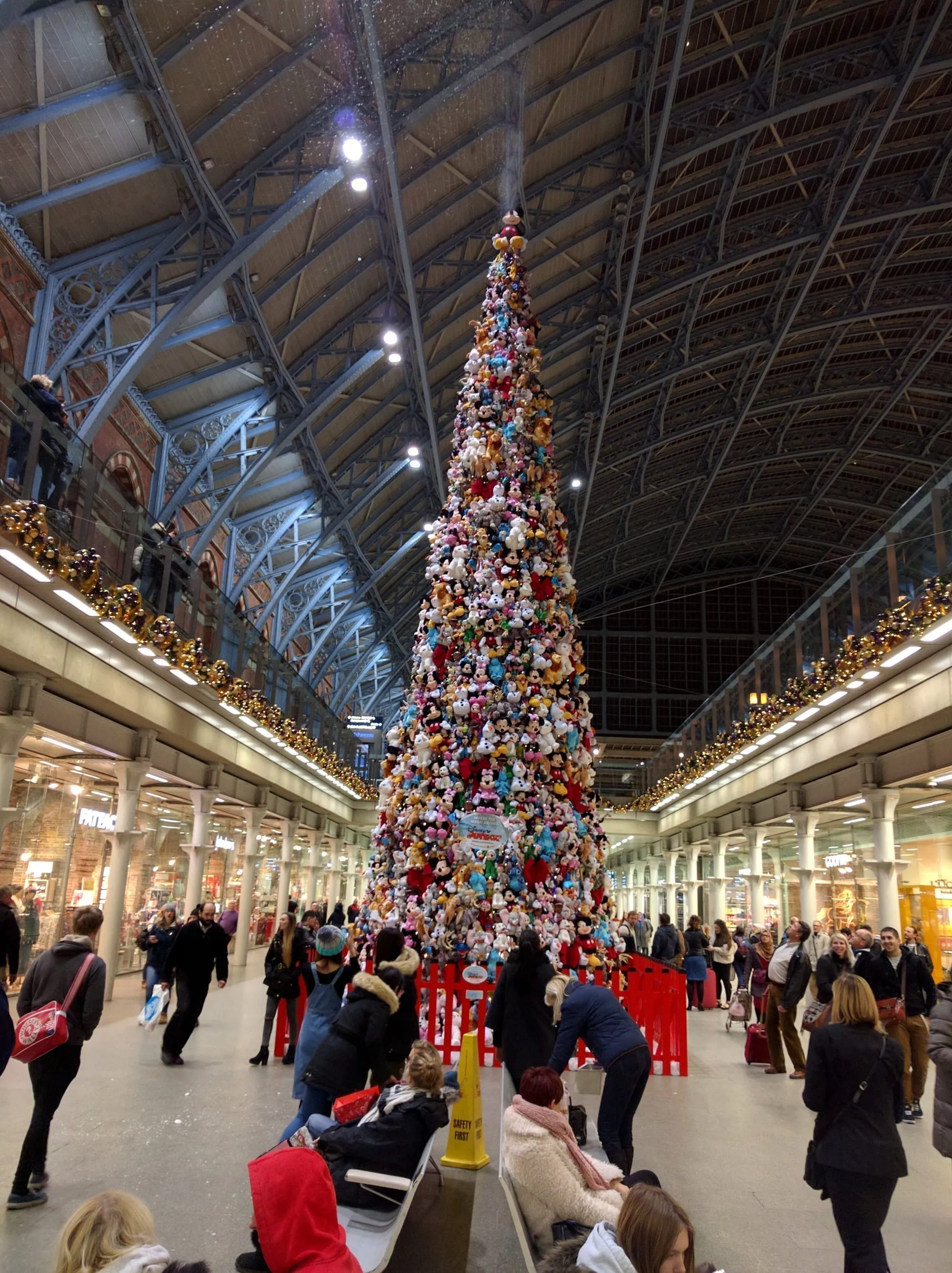 A towering Christmas tree built entirely from thousands of donated soft toys, under the wrought-iron and glass roof of St Pancras International station