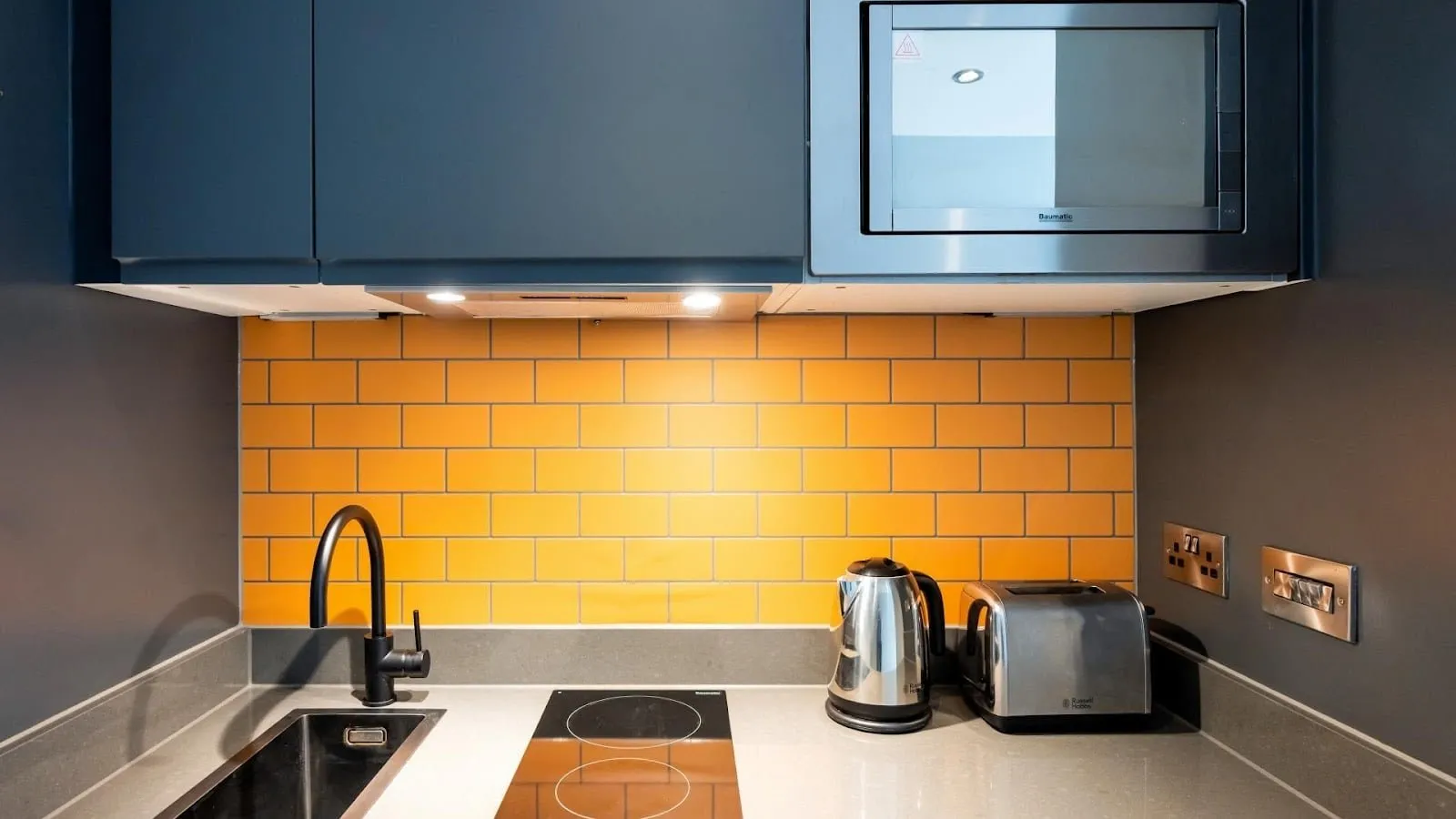 The kitchenette in a studio at Staycity Aparthotels Greenwich High Road, with a hob, microwave, kettle and toaster