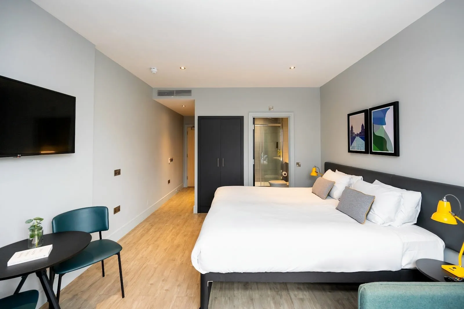 A studio at Staycity Aparthotels Greenwich High Road with a double bed, a wall-mounted television and the shower room beyond
