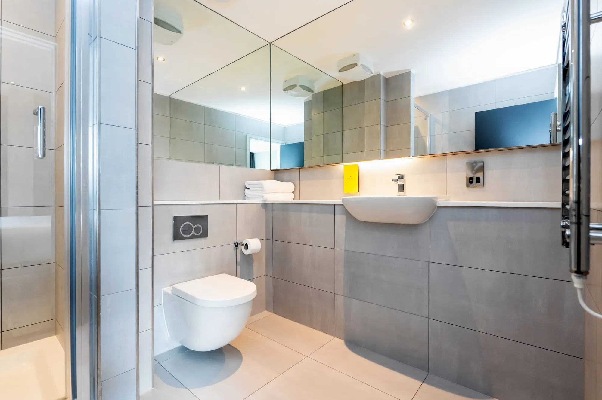 The bathroom at Staycity Greenwich High Road, with grey tile and a mirrored wall
