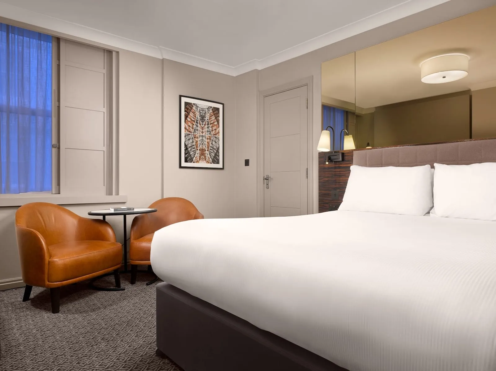 A guest room at the Strand Palace, with two leather armchairs and a table beside the window