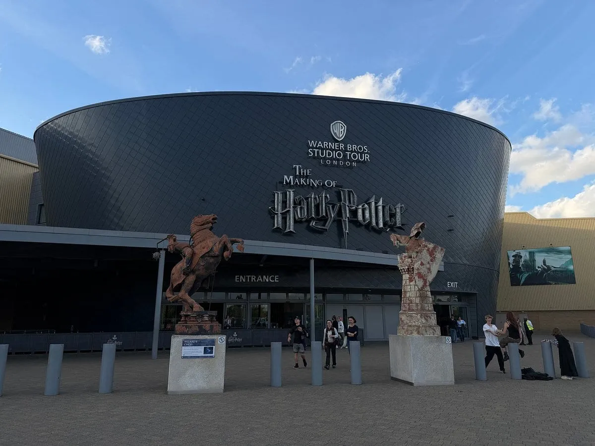 The curved black frontage of Warner Bros. Studio Tour London, with the Making of Harry Potter lettering above the entrance and the chess knight statues outside