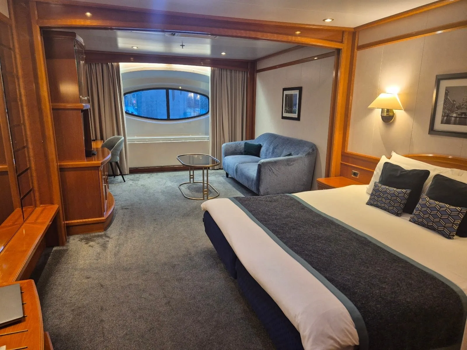 A room on the Sunborn London with a double bed, a sofa and an oval porthole window