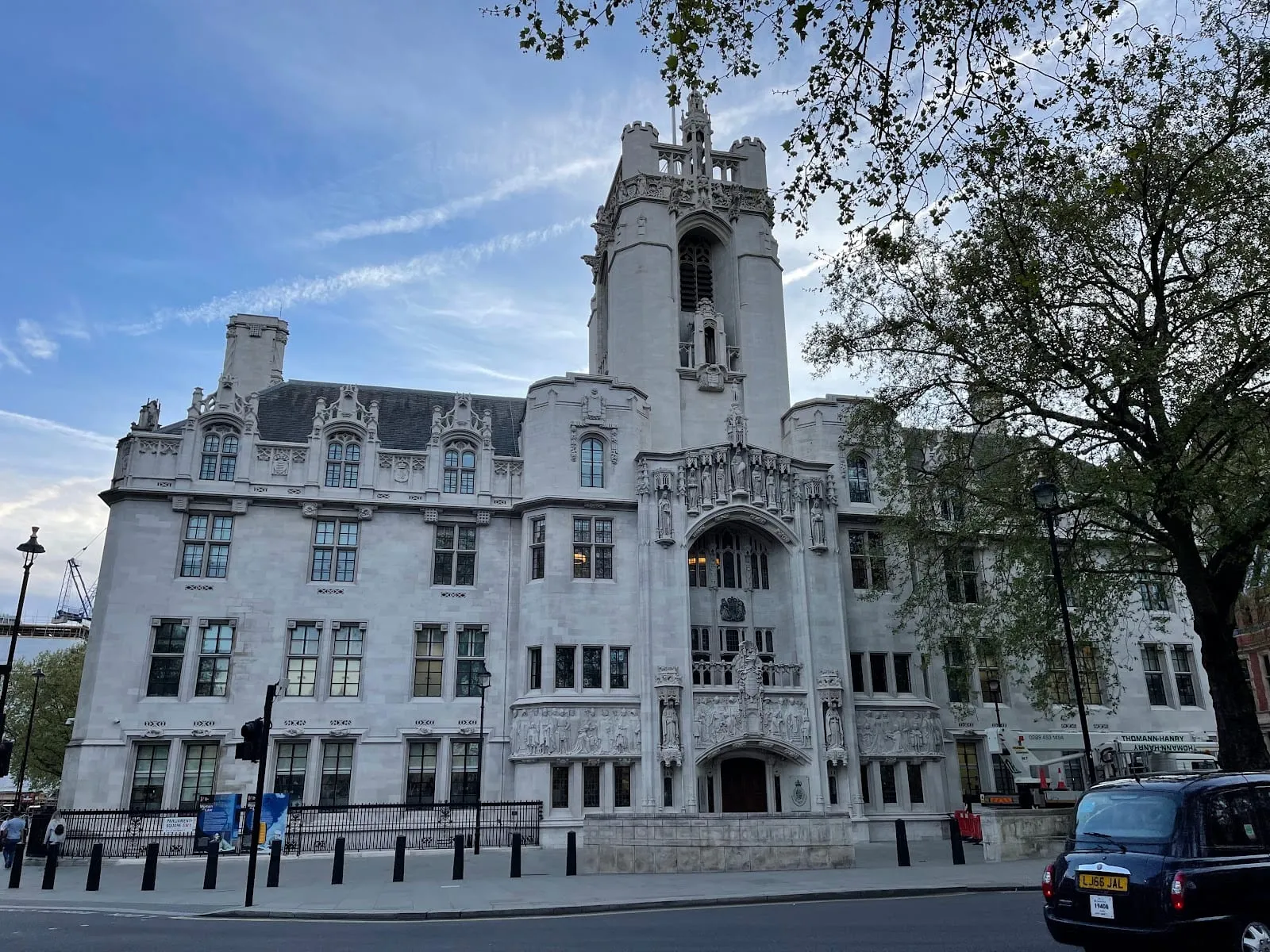 Middlesex Guildhall on Parliament Square, a white Gothic building with a carved stone tower and a sculpted relief above the entrance, a black cab passing