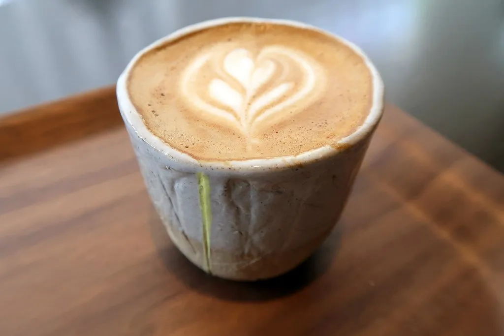 A flat white in a ceramic cup on a wooden tray