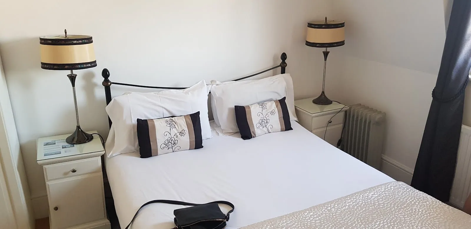 A double room at The Angerstein Hotel with a black iron bedstead and two table lamps