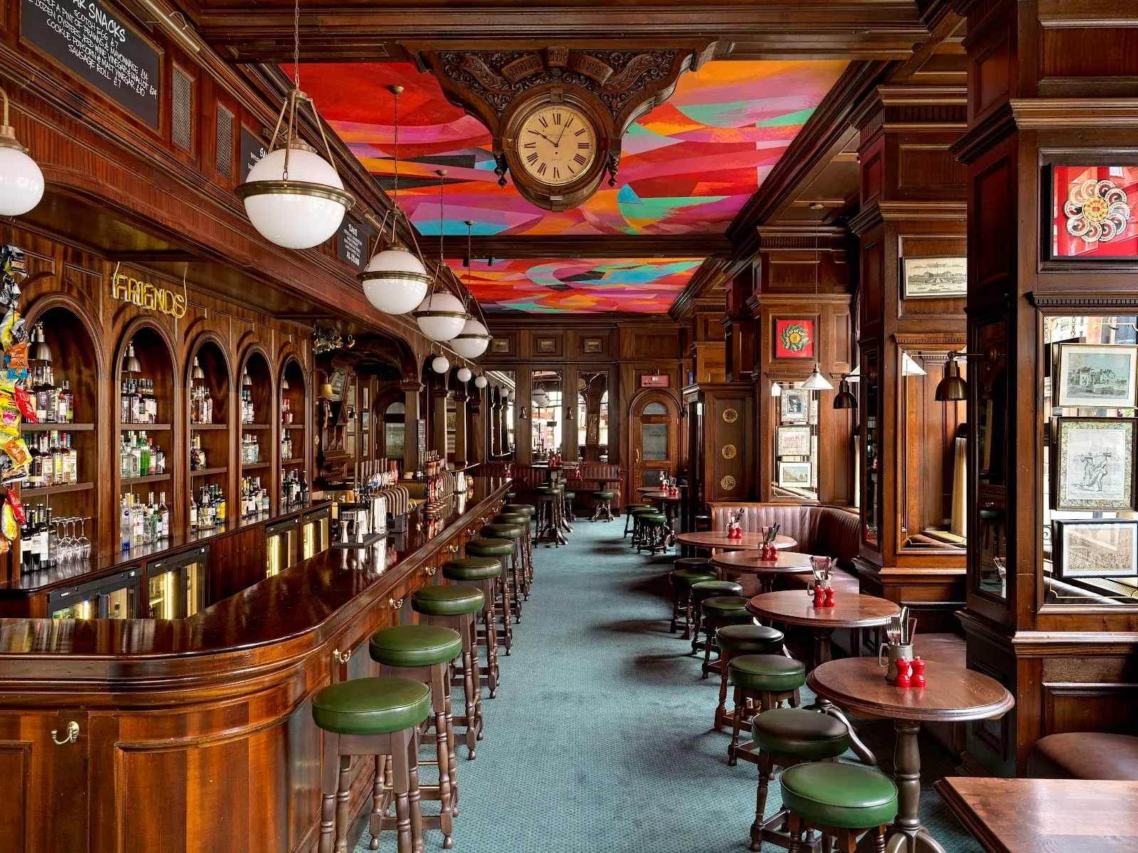 Inside The Audley, with a colourful abstract mural on the ceiling above the bar and green stools