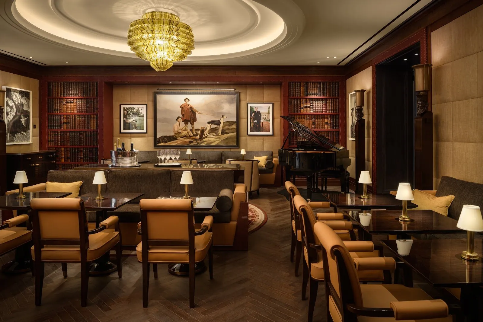 The bar at The Beaumont Mayfair, with leather armchairs, bookshelves and a painting of a man walking a dog on a lead