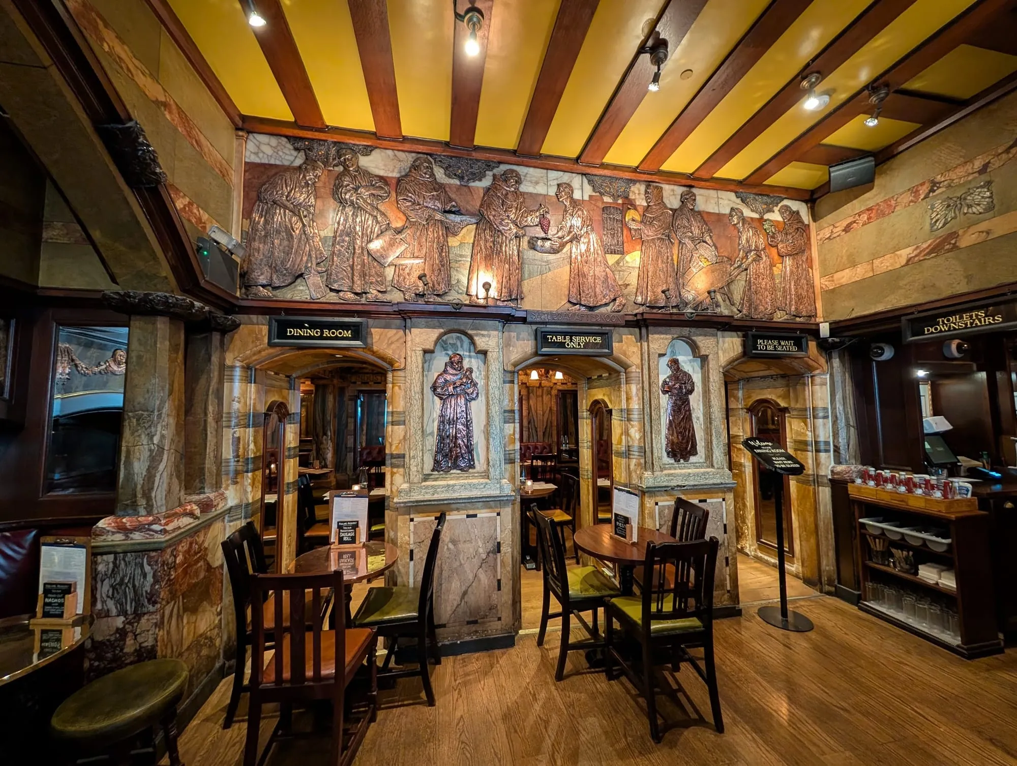 A frieze of bronze-relief friars above marble-panelled dining alcoves inside The Blackfriar, with carved marble columns and doorways below