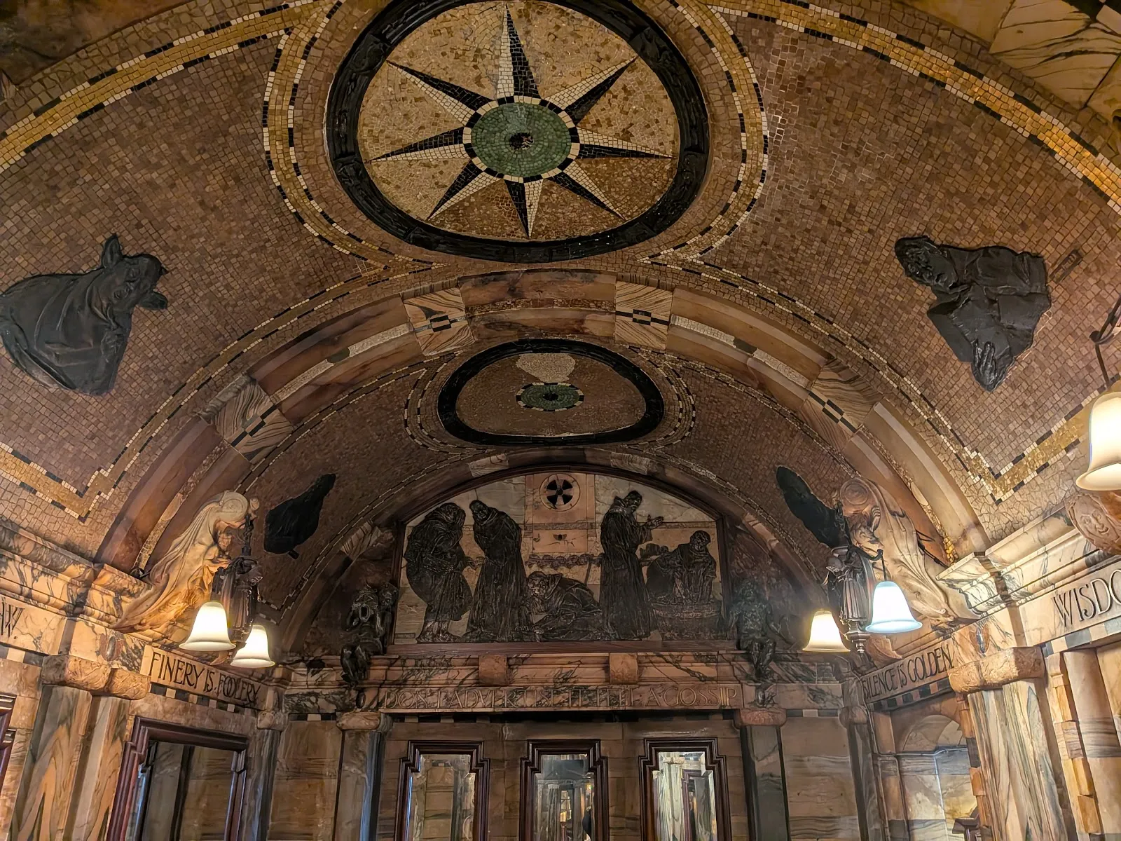 The gold mosaic ceiling and bronze relief friars inside the Blackfriar, with carved mottoes set into the marble walls