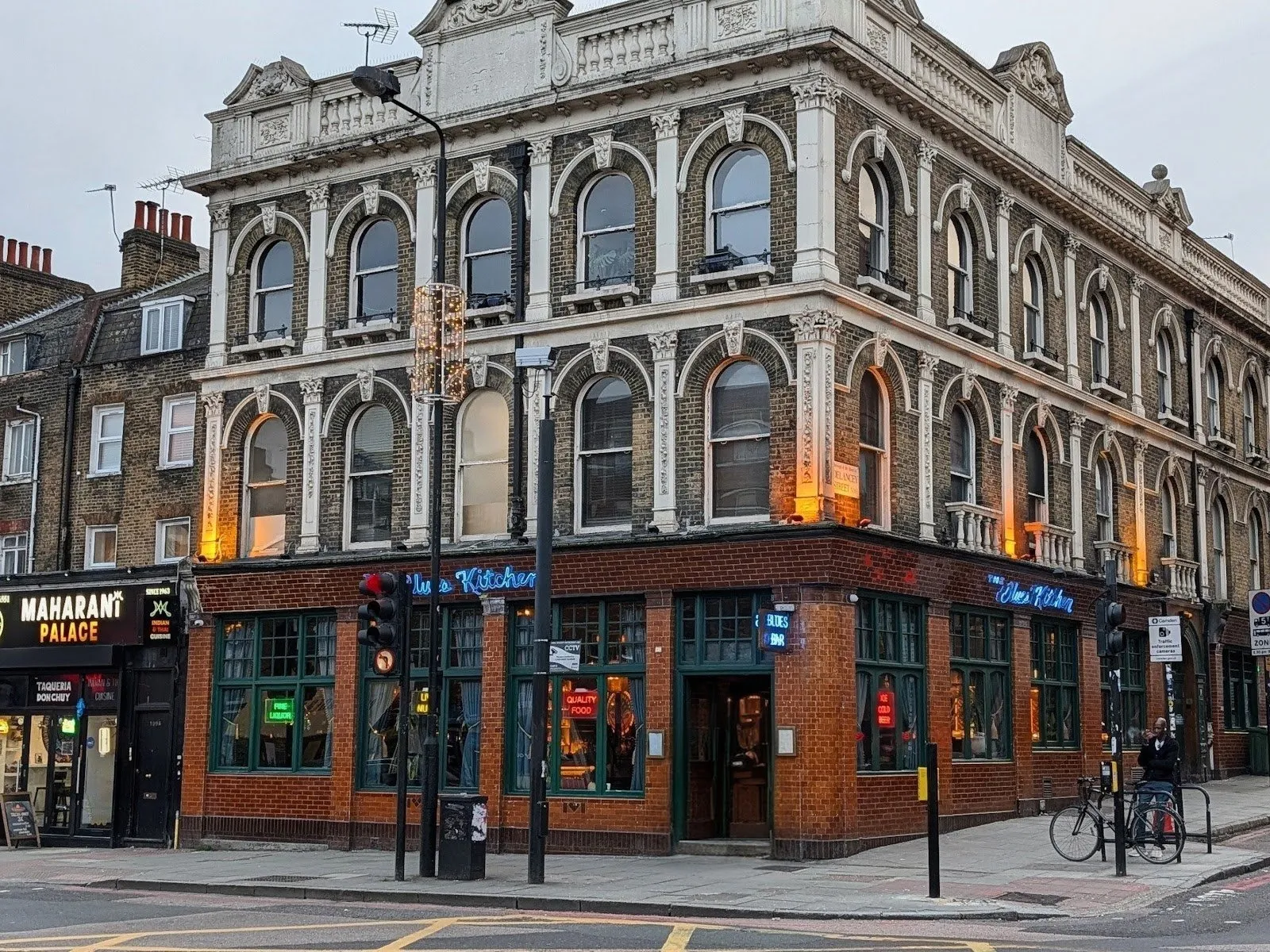 The corner building of The Blues Kitchen on Camden High Street, its blue neon sign lit at dusk