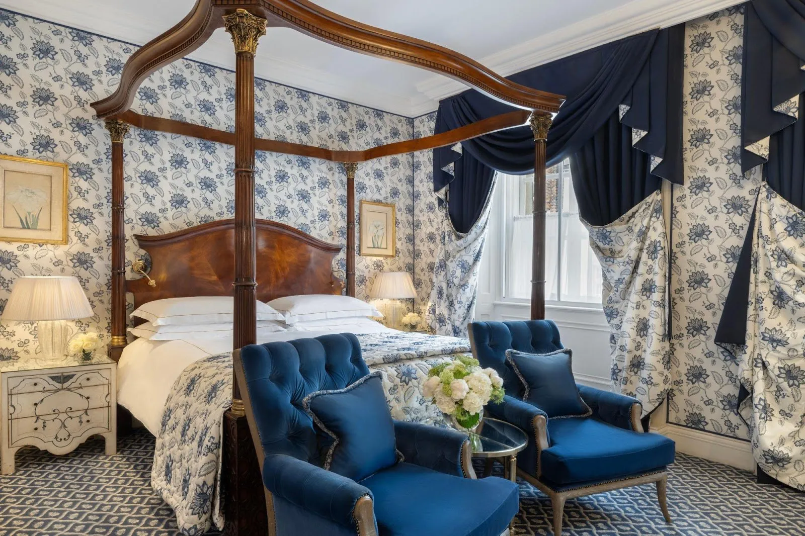 A four-poster bed at The Chesterfield Mayfair with blue and white floral wallpaper and matching curtains