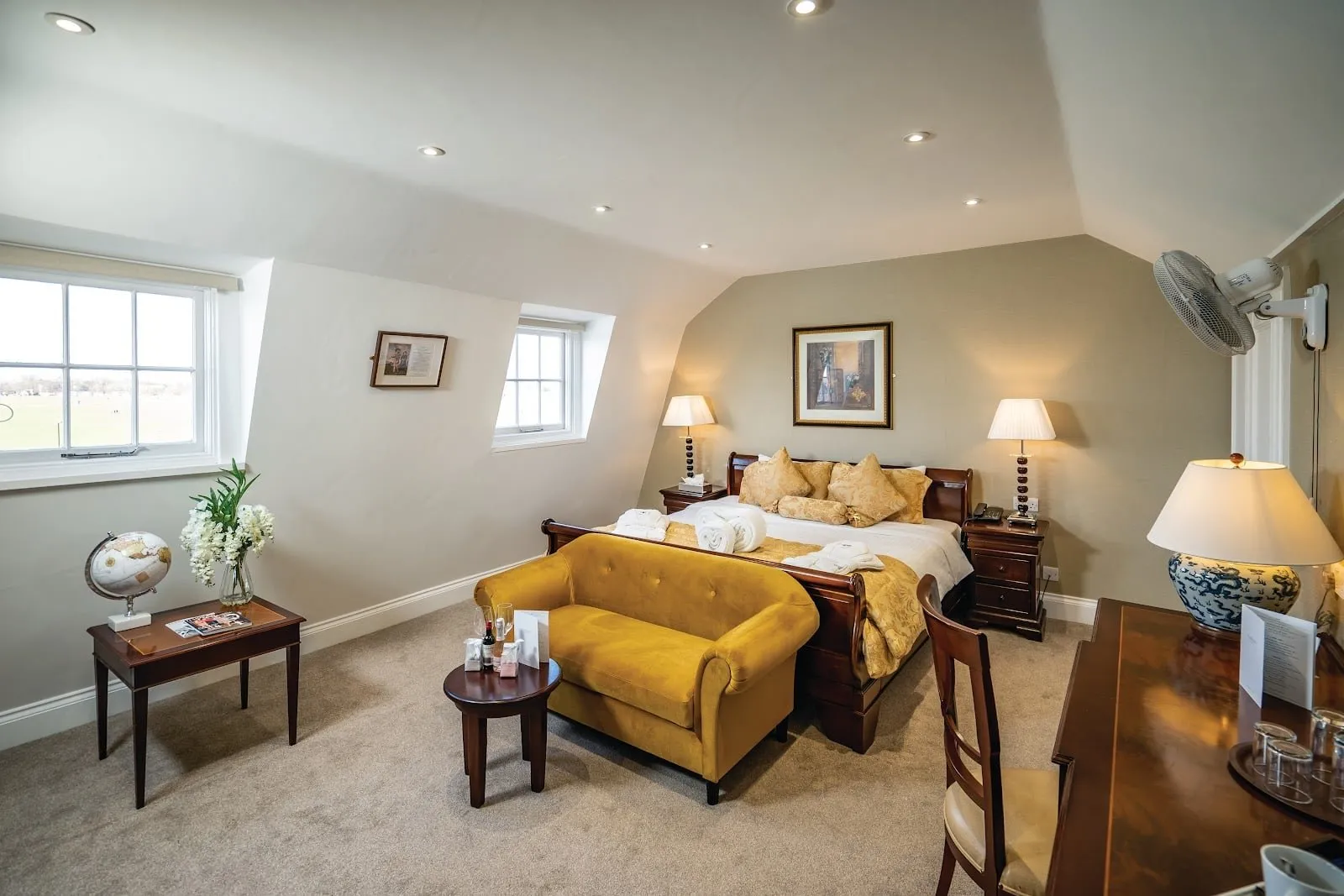An attic room at The Clarendon Hotel with a sleigh bed, a yellow sofa and windows over Blackheath