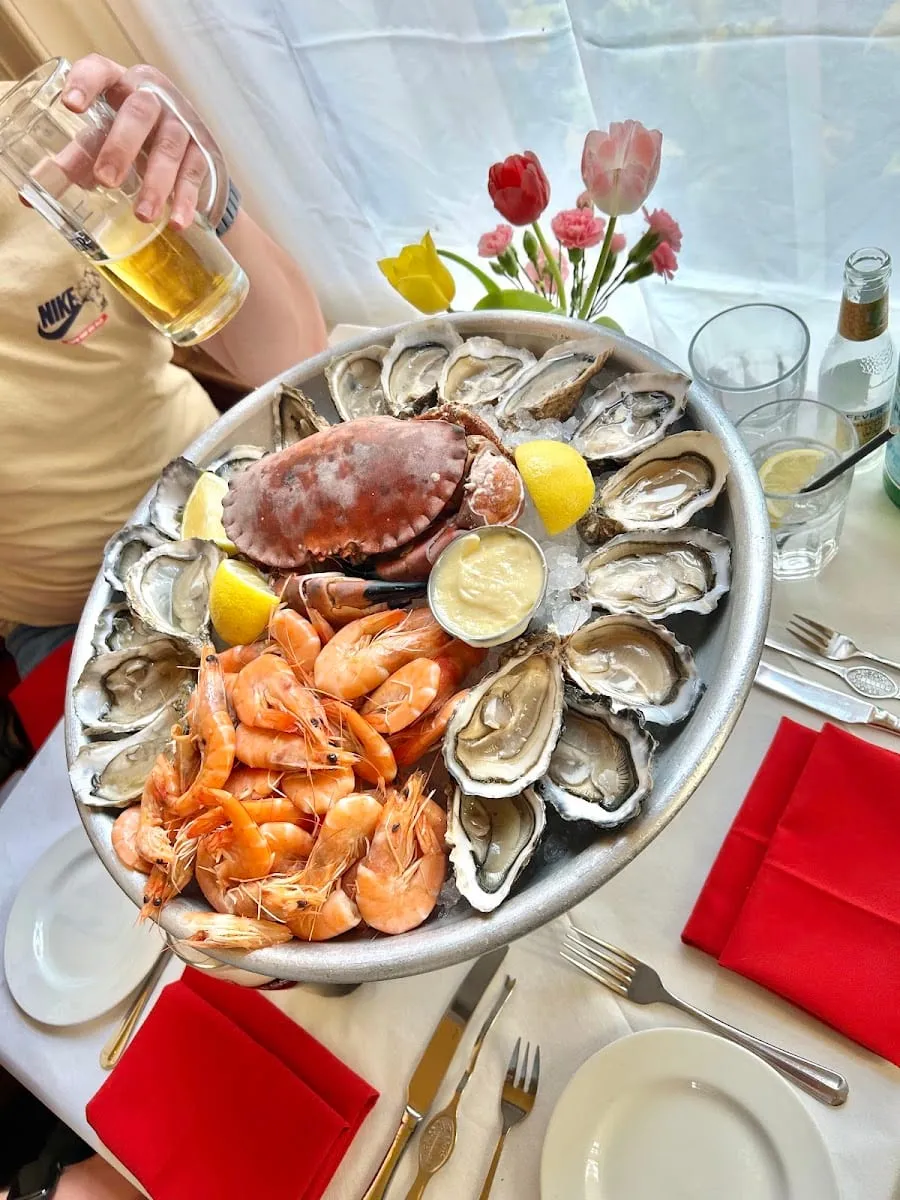 A whole seafood platter with oysters, a crab and prawns on ice, with lemon wedges and mayonnaise, on a table at The Cow