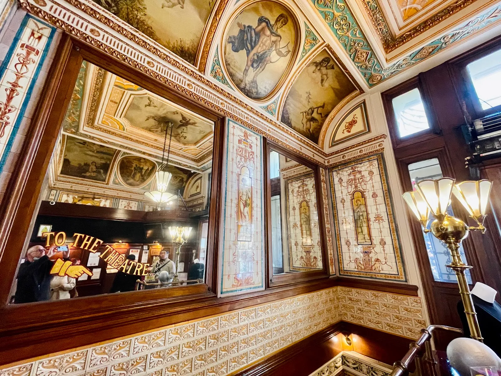 A gilded, mosaic-tiled ceiling and walls inside the Criterion, with a painted sign pointing the way to the theatre
